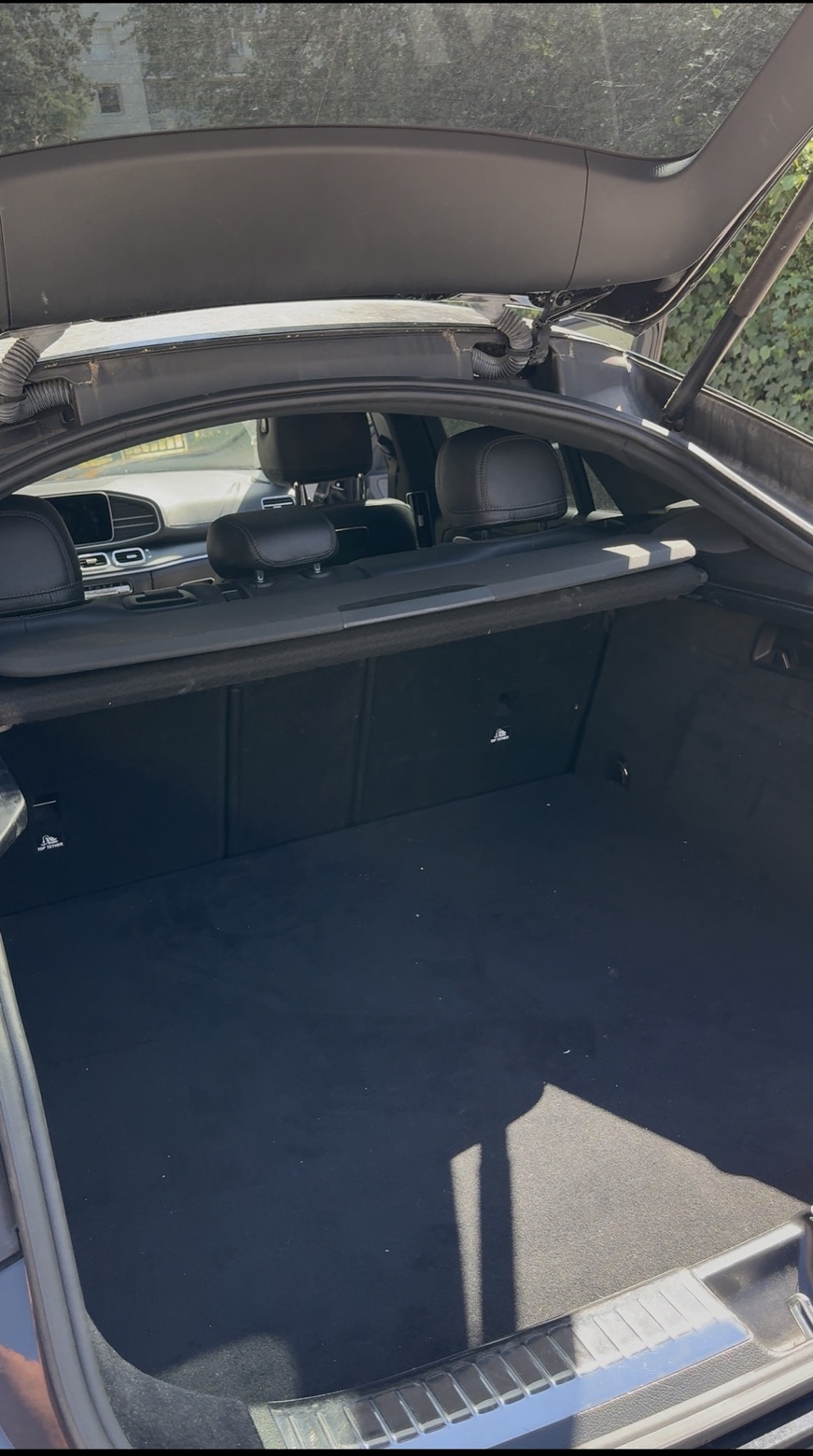 Coffre de voiture avant nettoyage : moquette terne, poussière et débris